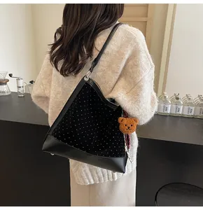 Detail of black velvet bucket bag with silver rhinestones and a plush bear pendant