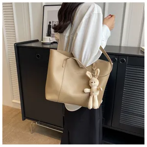 Detailed view of khaki large tote bag with cute plush bunny charm on shoulder