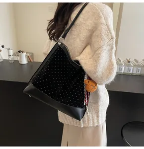 Detail of black velvet bucket bag with white dots, leather strap and cute bear charm