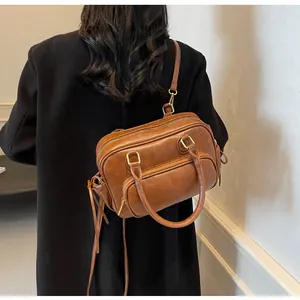 Detail view of vintage brown PU leather Boston bag with gold hardware and shoulder strap