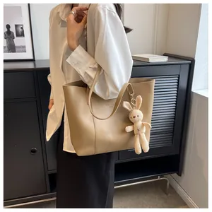 Detail of beige tote bag with smooth PU leather finish and cute white rabbit plush charm