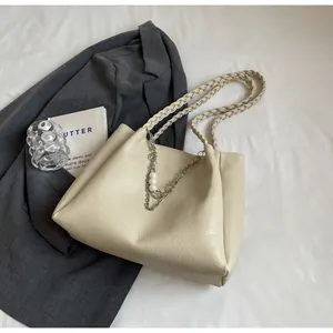 Detail of off-white tote bag with braided straps, silver metal chains and pearl accents
