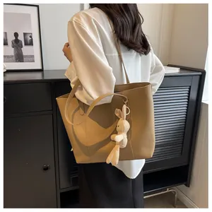 Khaki PU leather tote bag with plush bunny pendant shown on shoulder in a chic urban setting