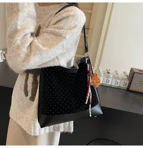 Detail of black suede tote bag with white polka dots and cute bear plush charm