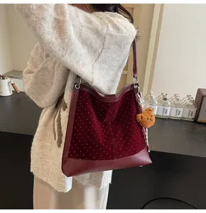 Detail of burgundy suede bucket bag with white polka dots and cute bear pendant