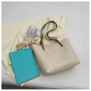Macro detail of cream tote bag with olive green handles and gold logo branding