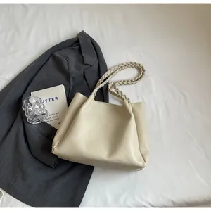 Detail of cream tote bag featuring textured PU leather and elegant woven shoulder straps