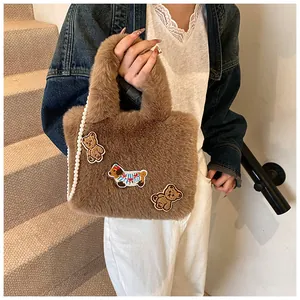 Details der flauschigen braunen Beuteltasche mit süßen Bären- und Hunde-Stickereien