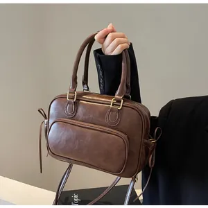 Detail of vintage brown leather bag featuring metal zippers and dual handles
