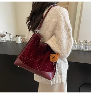 Detail of burgundy velvet tote bag with white dots and a cute brown plush bear charm