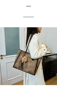 Detail view of large brown vintage tote bag with plush charm in minimalist interior