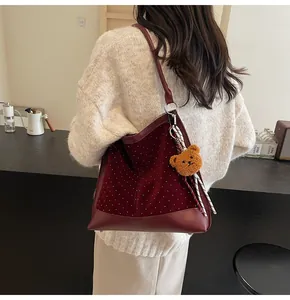 Detail of burgundy velvet tote bag with white polka dots and cute bear pendant
