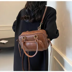 Rear view of a model wearing a retro dark brown leather crossbody bag over a black coat