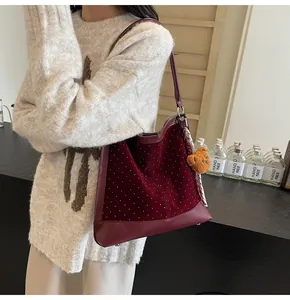 Detail of burgundy velvet tote bag with white polka dots and a plush bear charm on model
