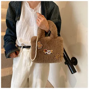 Nahaufnahme der braunen Plüsch-Beuteltasche mit Bärenstickerei und eleganter Perlenkette