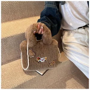 Detail der flauschigen braunen Beuteltasche mit Cartoon-Patches und feiner Perlen-Schulterkette