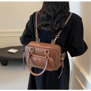 Close-up of brown vintage leather backpack with golden buckles worn over a black coat