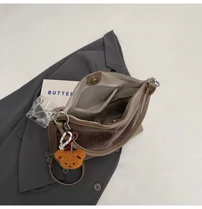 Detail of brown suede bucket bag with white polka dots, plush bear charm and zip pocket