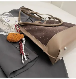 Detail of vintage suede polka dot tote bag with metal feet and cute teddy bear charm