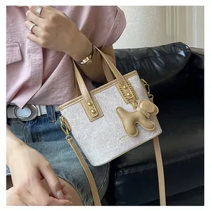 Detail der beigen Beuteltasche mit braunen Griffen und einem niedlichen Hundeanhänger