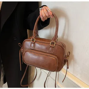Detail of vintage brown leather handbag with large front zipper pocket and tassel accent