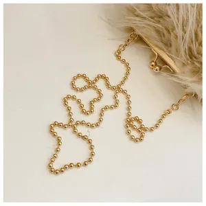 Detail of soft beige plush bag featuring vintage metal clasp and golden bead chain strap