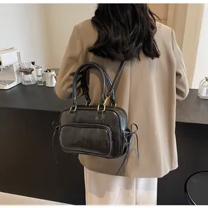 Detail of dark gray vintage leather handbag with side bow on a coffee shop background