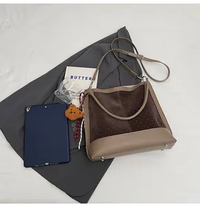 Detail view of coffee suede bucket bag with white dots, bear charm and striped scarf