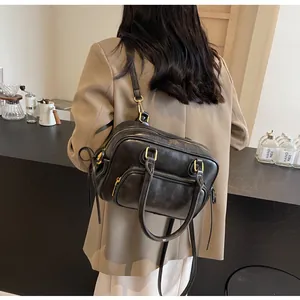 Detail view of retro black boston handbag with golden hardware and adjustable strap