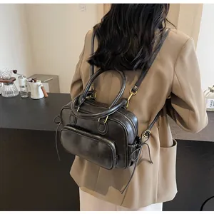 Retro black leather backpack with brass zippers shown in a cozy cafe setting