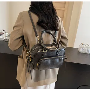 Detail of a black faux leather Boston-style backpack with gold zippers and slim straps