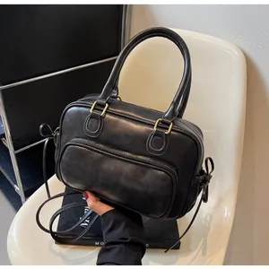 Detail view of a vintage black matte leather bowling bag with gold zippers and side bows