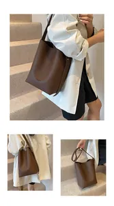 Detail of dark brown pebble leather bucket bag showing embossed text and crossbody strap