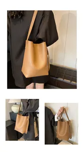 Detail of brown litchi pattern leather bucket bag showing adjustable strap and fashion stamp