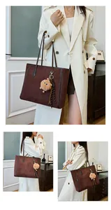 Detail of coffee brown suede tote bag with plush charm and leather handle trim