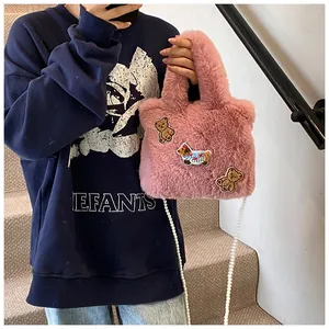 Detailansicht der rosa Plüsch-Eimertasche mit Cartoon-Stickerei und Perlenkette