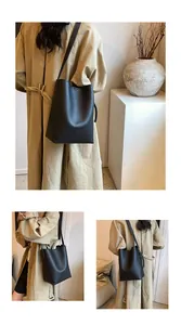 Close-up of black lychee-grain leather bucket bag with embossed logo and stone decor