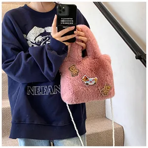 Detailansicht der rosa Plüschtasche mit Cartoon-Patches und langer Perlenkette