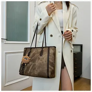 Detailed side view of a vintage marble-textured tote bag with a plush pompom accessory