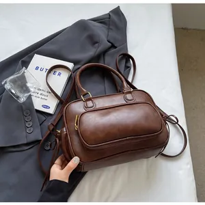 Detailed view of deep brown vintage PU leather handbag with front zipper pocket and hardware