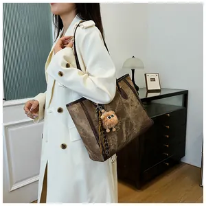 Close-up of a large dark brown tote bag with marble texture and monster charm details