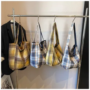 Detail of four colorful plaid tote bags hanging on a rack with Scottish tartan patterns