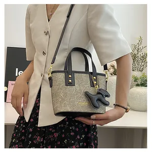 Minimalistische beige Beuteltasche mit schwarzen Griffen und süßem Hundeanhänger