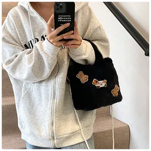 Detail der schwarzen Plüsch-Beuteltasche mit Teddy-Patches und weißer Perlenkette