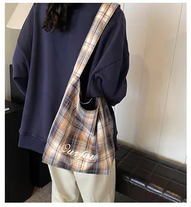 Close-up of yellow plaid tote bag with wide strap and Ourfau Party printed text