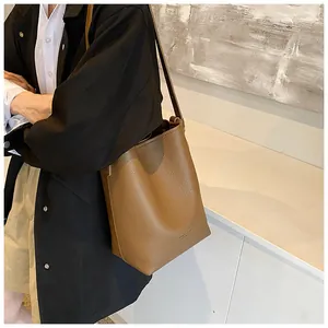 Detail of brown litchi pattern leather bucket bag showing texture and slim shoulder strap