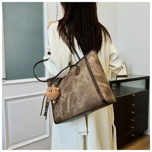 Detail view of large faux leather tote bag with vintage texture and plush charm