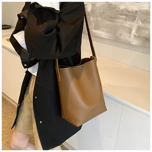 Detail view of brown lychee grain leather bucket bag with gold foil branding and wide strap