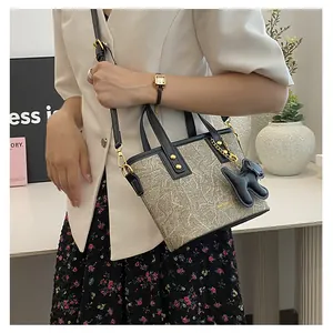 Detail der minimalistischen Beuteltasche mit Lederbesatz und Welpen-Anhänger auf Tisch