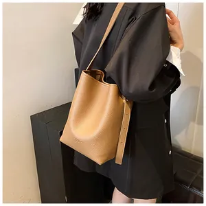 Detail of dark camel bucket bag featuring premium lychee grain leather and adjustable strap